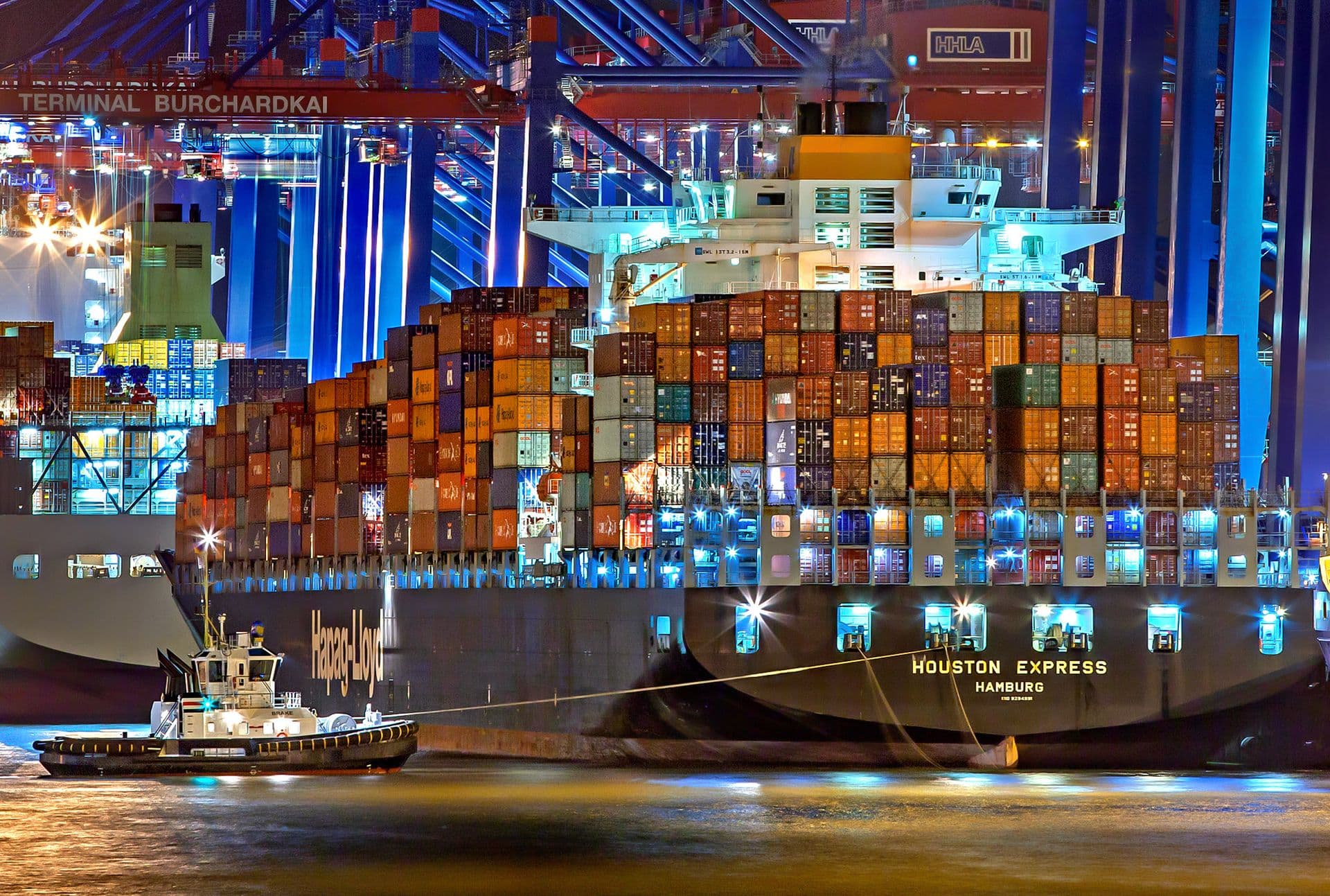 Container ship being loaded by cranes at an illuminated port terminal at night